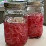 Mason jars filled with red onions being pickled