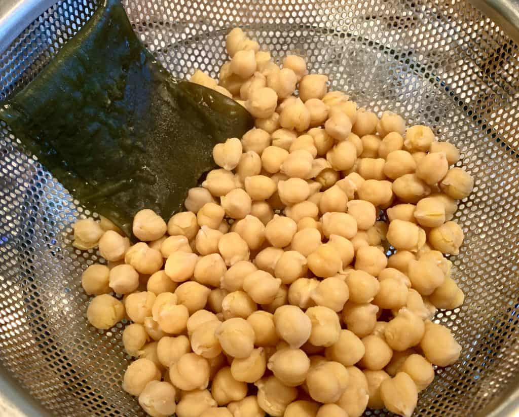 Chickpeas and kombu in a strainer over a bowl
