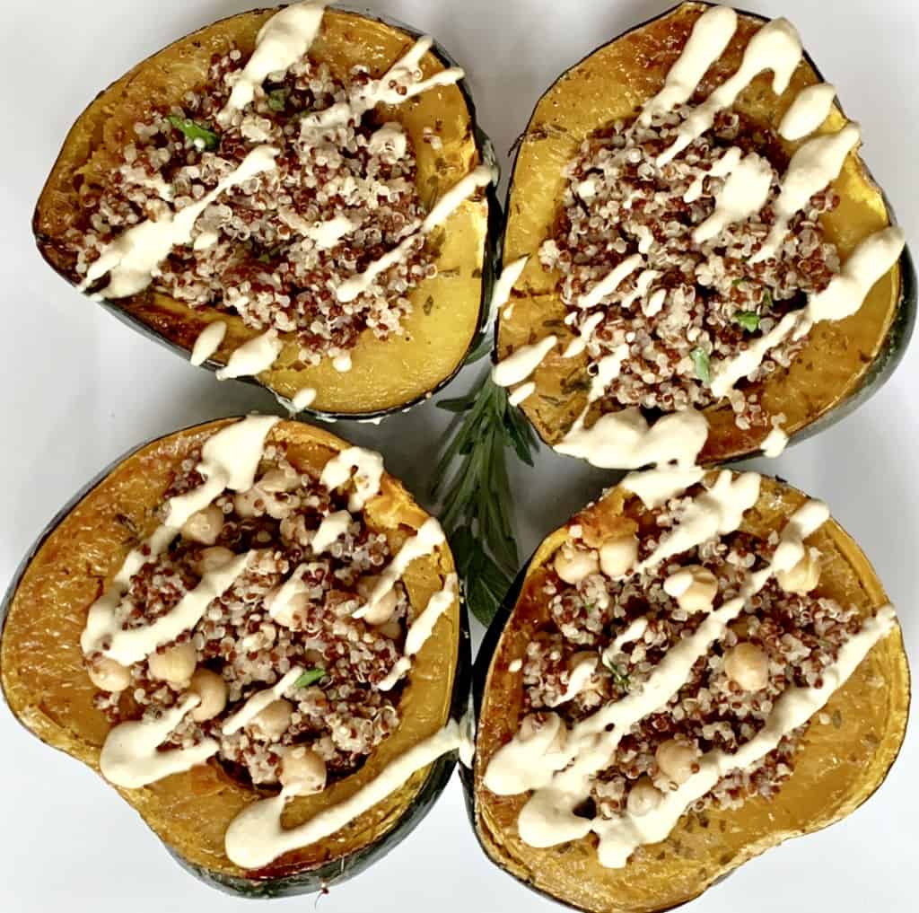 Roasted and stuffed acorn squash plated with drizzle of cashew cream