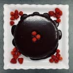 Top view of almond torte with chocolate nut butter icing dressed with raspberries