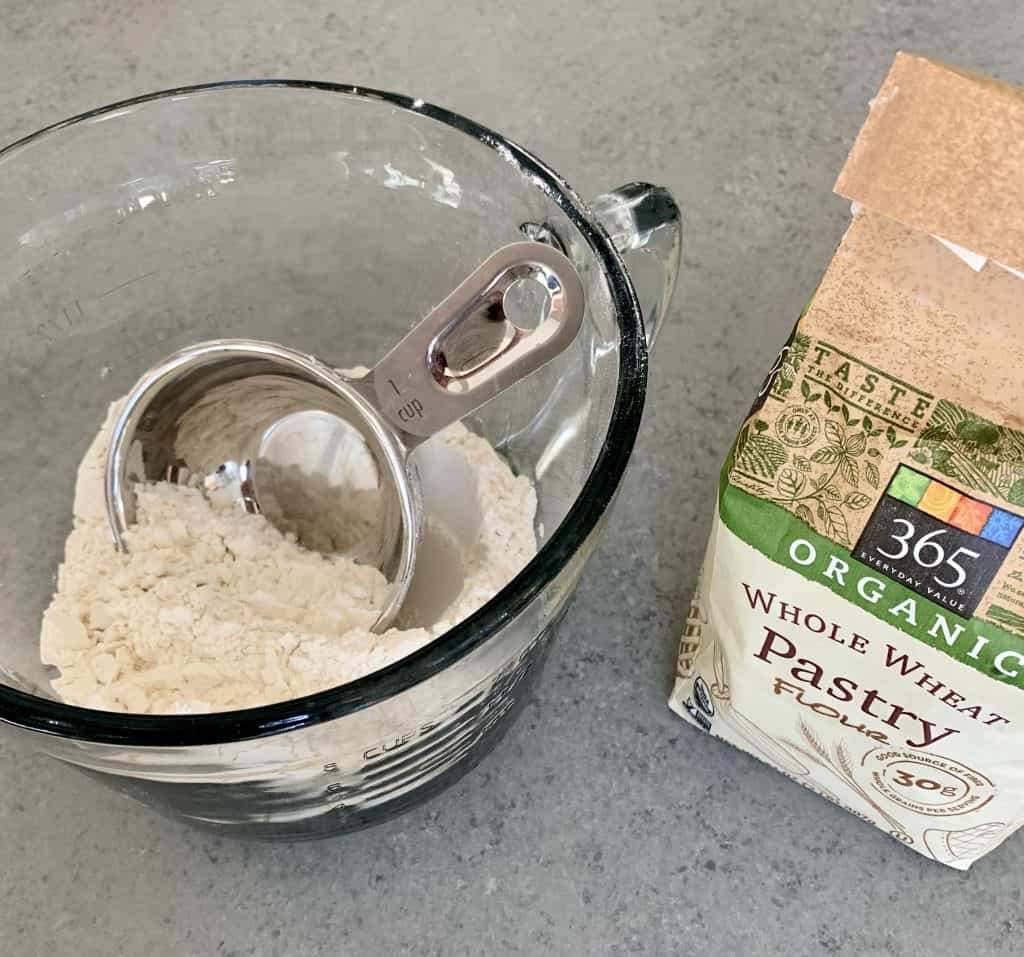 Flour in package and bowl with measuring spoon