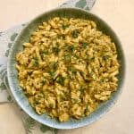 A bowl of food containing butternut squash macaroni and cheese topped with fresh herbs