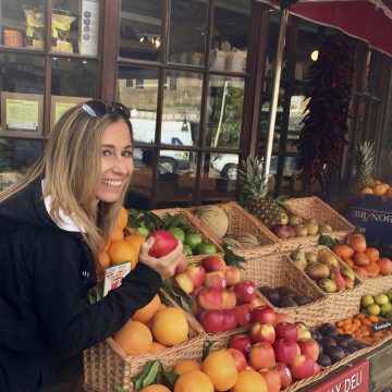 A picture of Chef Cindy stopping to pick an apple at a little market in the English countryside.