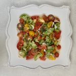 Assorted Garden Heirloom Tomato Basil Salad with Cippolini Onions on a decorative plate