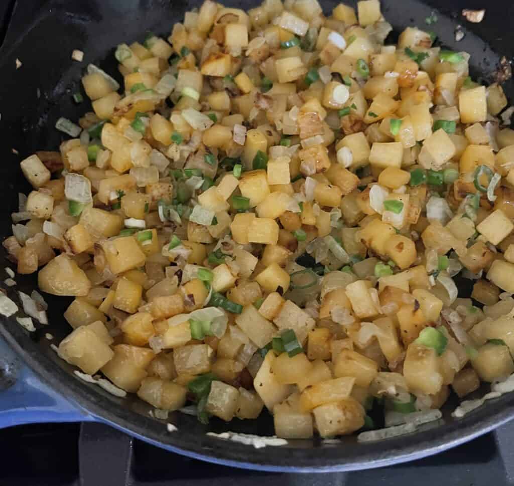 Skillet Rutabaga Home Fries being cooked up in a blue cast iron skillet