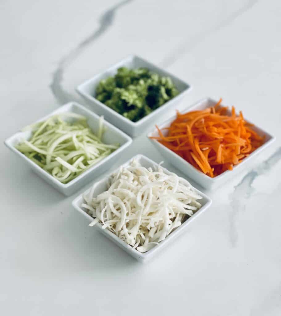 4 slaw ingredients separated in white square bowls